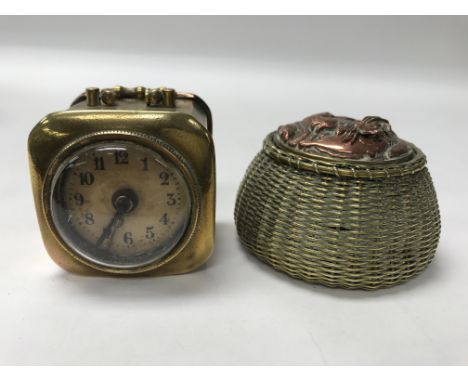 A small brass alarm clock together with an inkwell in the form of a basket of fish.