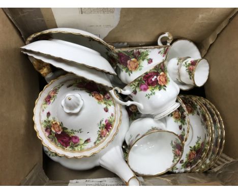 A box containing a collection of country rose including saucers, tea cups and a teapot.