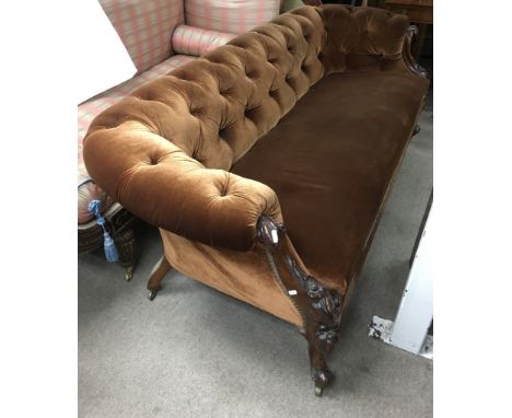 A carved wood, button back chaise on caster feet with brown velour upholstery.Approx 2.7cm