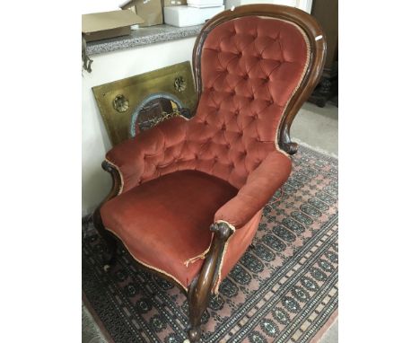A Victorian button back chair in red upholstery and raised on cabriole legs.