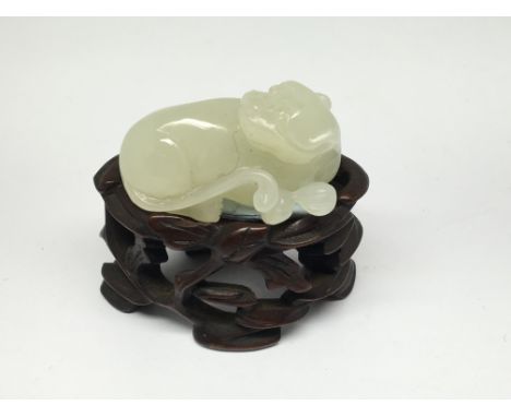 A further small light green carved jade model of a reclining dog, on carved wooden base. Approx 4cm