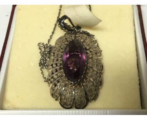 A Silver fillagree brooch set with an amethyst colour stone, with attached chain