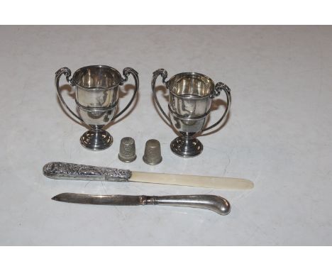 Two miniature silver trophy cups; a silver handled butter knife and a page turner