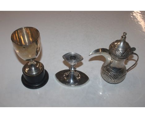 A silver trophy cup on stand; a silver dwarf candlestick; and an Eastern white metal coffee pot with curved spout 
