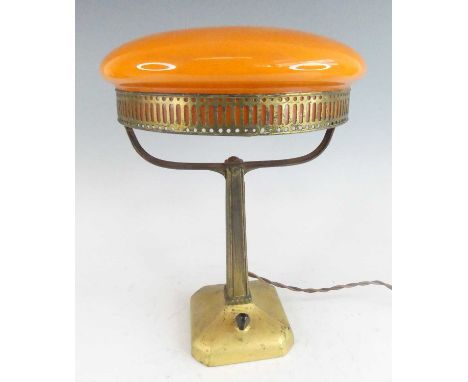 A circa 1900 Austrian Secessionist gilt metal table lamp, having a circular flattened orange glass domed inset shade, support