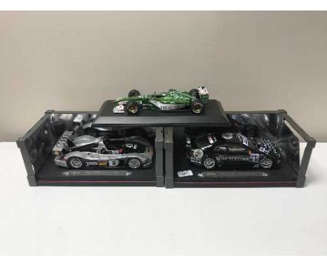 Three large scale Maisto racing cars on stands