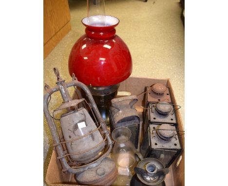 Lighting - A brass table oil lamp with red glass shade;  a paraffin lamp;  a brass chamber stick;  etc