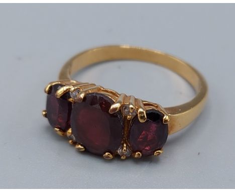 A yellow metal dress ring set with three garnets and four diamonds, 3.3gms, ring size R 