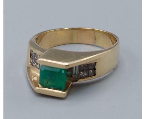 A 14ct gold ring set with a square emerald mounted above a band of diamonds 8.4gms, ring size R 