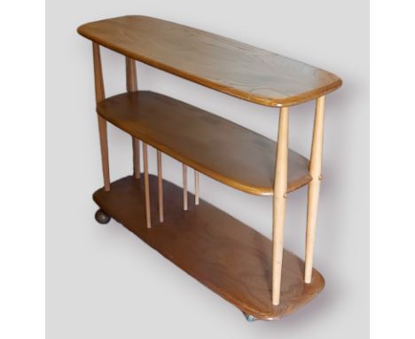 An Ercol blonde ash three tier bookcase with turned uprights upon Shepherd casters, 91cms wide, 31cms deep and 71cms tall 