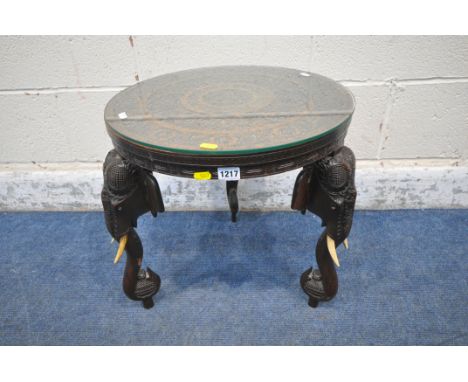 A 20TH CENTURY HARDWOOD ANGLO-INDIAN CARVED CIRCULAR TABLE, with foliate details, surrounding a Hindu god figure, raised on t