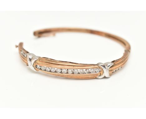 A 9CT GOLD DIAMOND BANGLE, eighteen diamonds channel set in a bi colour hinged bangle, approximate total diamond weight 1.00c