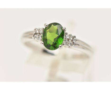 A 9CT GOLD GEM SET RING, an oval cut green stone assessed as tourmaline, flanked with four circular cut colourless topaz, lea