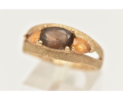 A 9CT GOLD GEM SET RING, an oval cut smoky quartz and two pear cut citrines, prong set in yellow gold with textured detail to