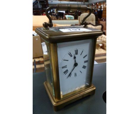 A French carriage clock in lacquered brass, enamelled dial set with Roman numerals.