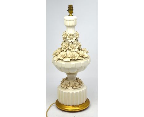 A cream ware table lamp with relief flower decoration on gold stand, height 66cm.   CONDITION REPORT  Crazing in places to bo