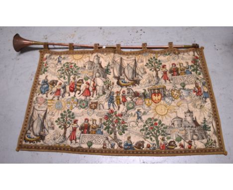 A vintage copper and brass hunting horn, length 121cm, suspending a decorative 16th century quilted-effect wall hanging with 