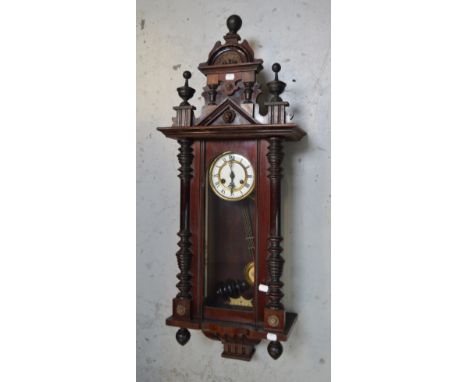 An early 20th century Vienna wall clock, white enamel dial set with Roman numerals, length 110cm.