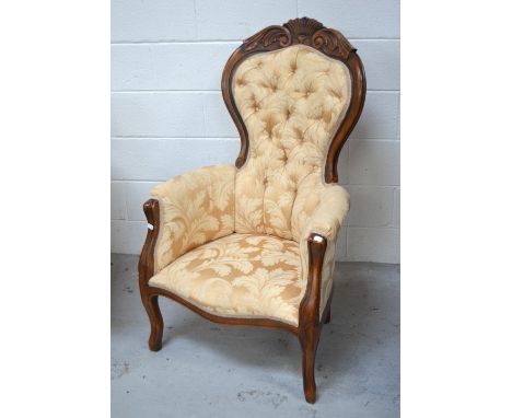 A 20th century walnut-framed spoon-back salon chair with scrolling arms and button back, carved top rail, raised on ogee supp