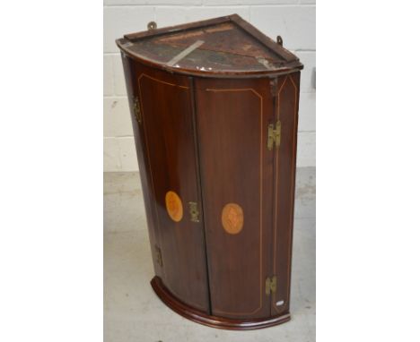 A late 19th century mahogany curved-front corner cabinet with two marquetry inlaid doors with brass furniture, height 94cm.  