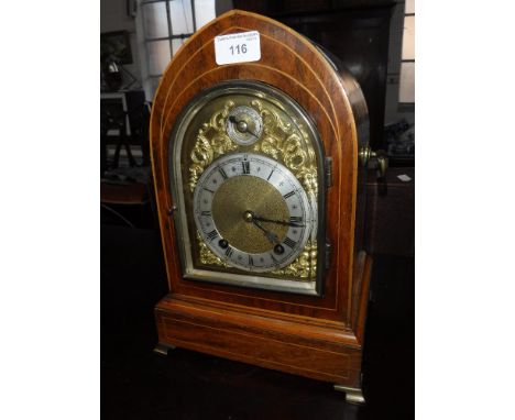 A LATE VICTORIAN MANTEL CLOCK in a rosewood case with boxwood stringing, the brass and silvered dial with applied rococo scro