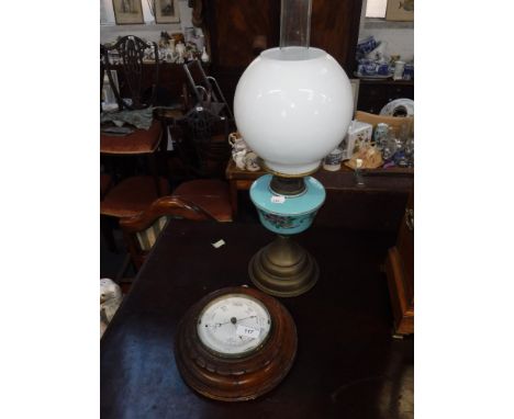 AN EARLY 20TH CENTURY WALL BAROMETER in a carved wood case and an oil lamp (2)