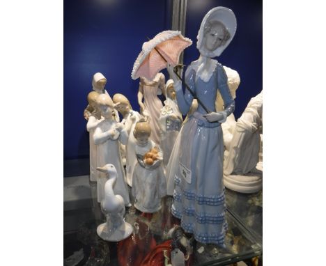 A LLADRO PORCELAIN FIGURE OF A LADY standing with a parasol and other similar Nao and Lladro figures and a duck