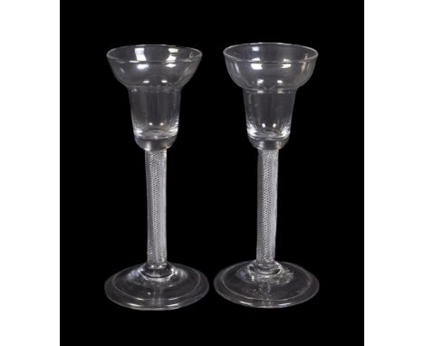 A pair of pan-topped air-twist wine glasses, mid 18th century, the stems filled with spiral threads and supported on a folded