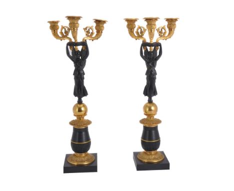 A pair of patinated and parcel gilt metal three light figural candelabra in Empire style, late 19th/early 20th century, each 