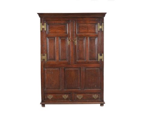 An oak hall or press cupboard, first half 18th century and later, with two panelled doors enclosing a hanging rail, and with 