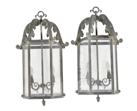 A pair of glazed and metal wall lanterns, 20th century, of trapezoid section, the foliate scrolled uprights descending to a d