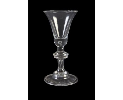 A baluster wine glass, circa 1740, the bell bowl with solid lower section and tear inclusion above a plain baluster stem with