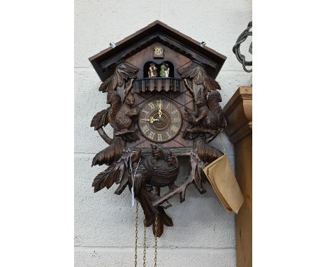 A German Schneider carved wood cuckoo clock with revolving dancing couples below the cuckoo, above squirrels and birds, 45cm 