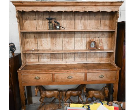 A large antique pine dresser with plate rack over three drawer base with cupped handles and shaped supports, 190 cm wide x 44