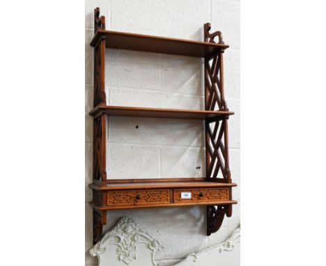 A hardwood three-tier wall shelf with open trellis side panels and two drawers, in the Chinese Chippendale manner 