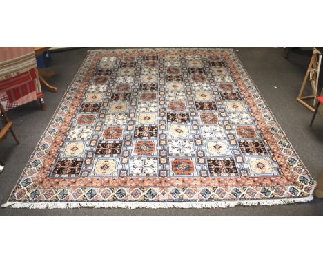 A large Moroccan rug. The central panel featuring multiple motifs in a grid pattern, surrounded by pink, cream and blue borde