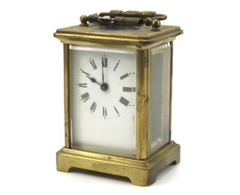 A brass carriage clock. The white dial with Roman numerals, carrying handle to the top, unknown maker, H11cm