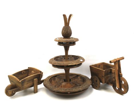 Two wooden models of a wheelbarrow and trough together with an Australian carved wooden 'pineapple' stand. The stand separate