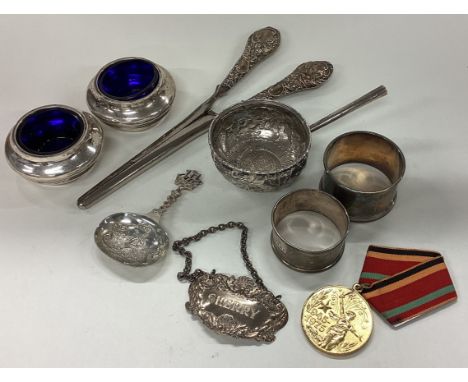 A box containing napkin rings, wine labels, caddy spoon etc. Approx. 138 grams of weighable silver. Est. £30 - £50.