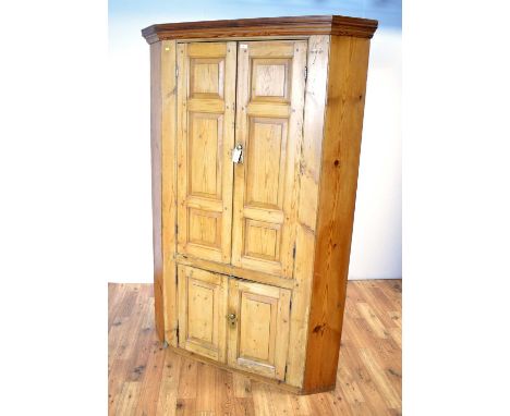 A vintage pine barrel back four-door corner cupboard, the upper section with stepped cornice and double door cabinet enclosin