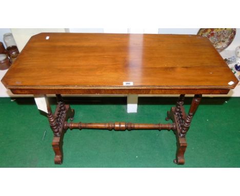 An Edwardian Walnut Occasional Table, the rectangular top with cut corners, on turned supports and ceramic castors.