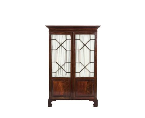 AN EDWARDIAN MAHOGANY WARDROBE of compact proportions, with dentil cornice above twin astragal glazed panel doors and raised 