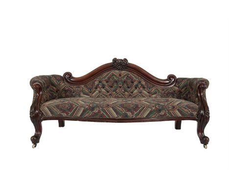 A LARGE VICTORIAN MAHOGANY FRAMED UPHOLSTERED BUTTON BACK COUCH, the arch crest with carved vine and fruit and raised on scro