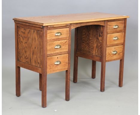 An early 20th century Arts and Crafts style oak desk, fitted with an arrangement of drawers, height 77cm, width 115cm, depth 