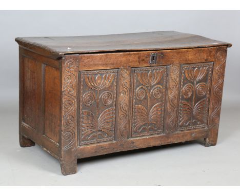 A late 17th century oak coffer with hinged lid, the triple panel front later carved with flowerheads and stems, width 130.5cm