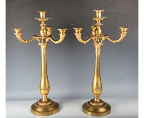A pair of 19th century Regency style ormolu four-light candelabra, each elongated baluster stem supporting a central sconce a