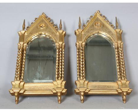 A pair of late 19th century Gothic Revival giltwood and gesso wall mirrors of arched architectural form, with incised foliate