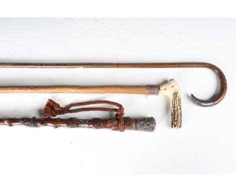 A late Victorian holly walking cane with silver mounted handle and carved shaft, length 86cm, together with two other walking