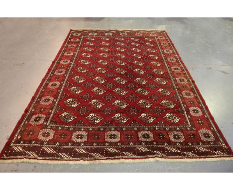 A Turkestan style carpet, mid-20th century, the claret field with overall offset guls, within a sunburst gul border, 330cm x 