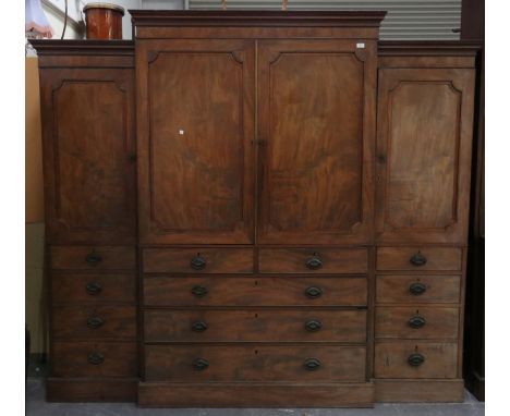 A George III mahogany breakfront wardrobe, the moulded pediment above a central linen press cupboard and two short and three 